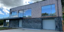 Pont House in Fowey by green and rock. Wood and stone front.